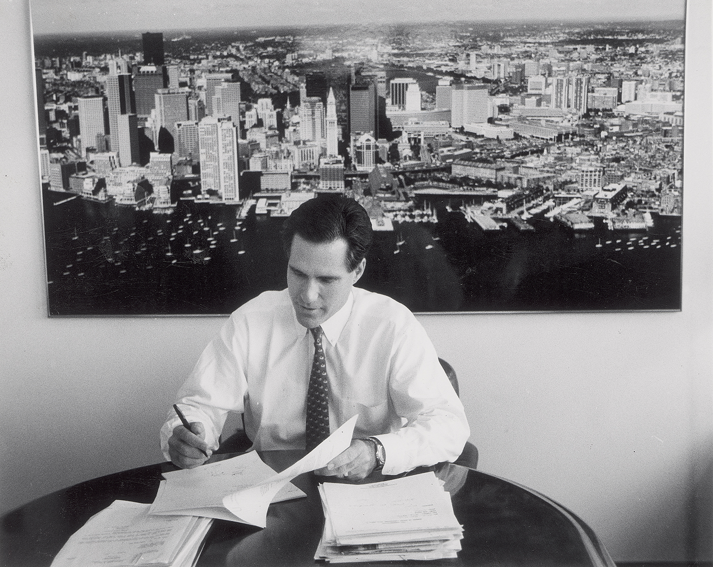 Mitt Romney sits at a table working on papers