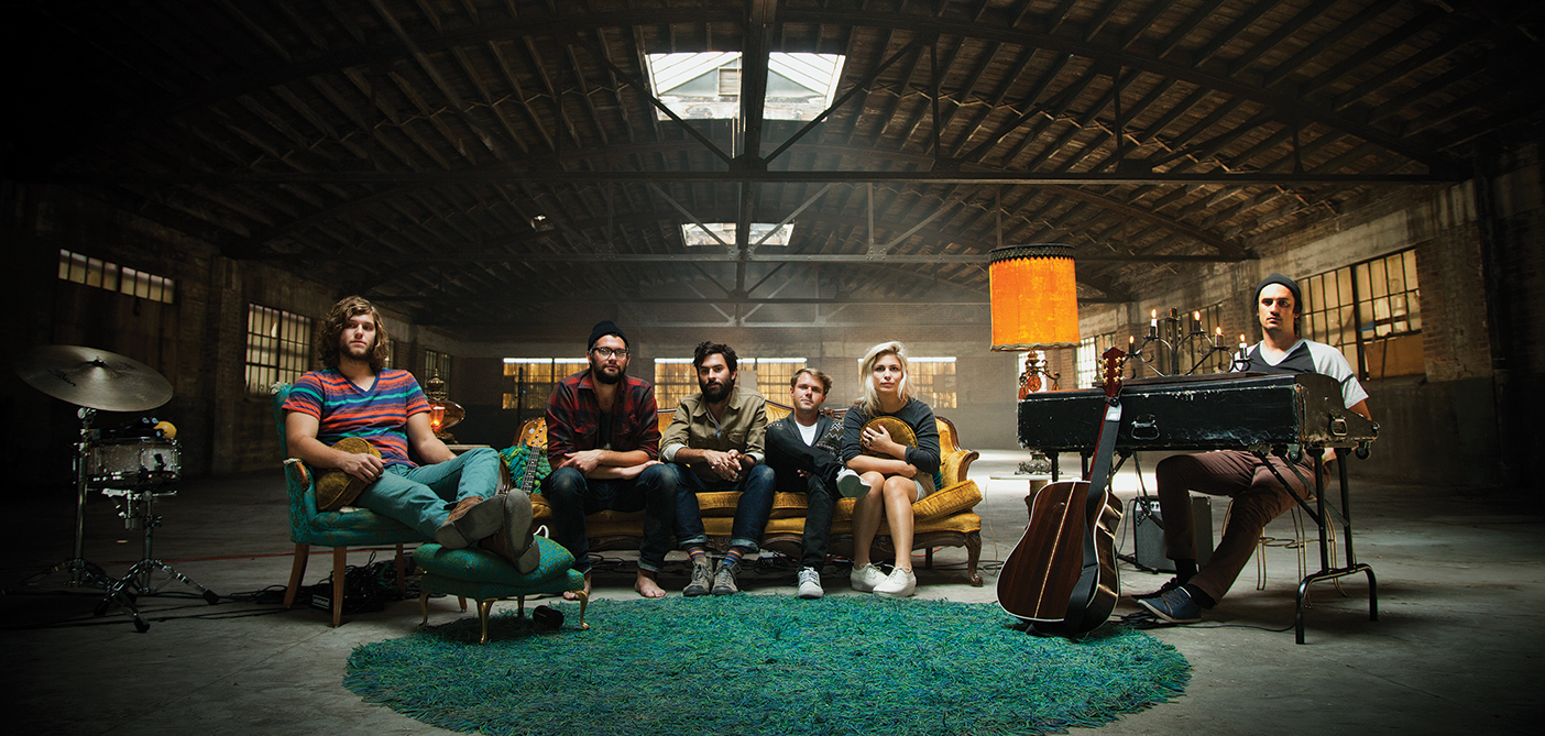band members sit on a couch in a warehouse