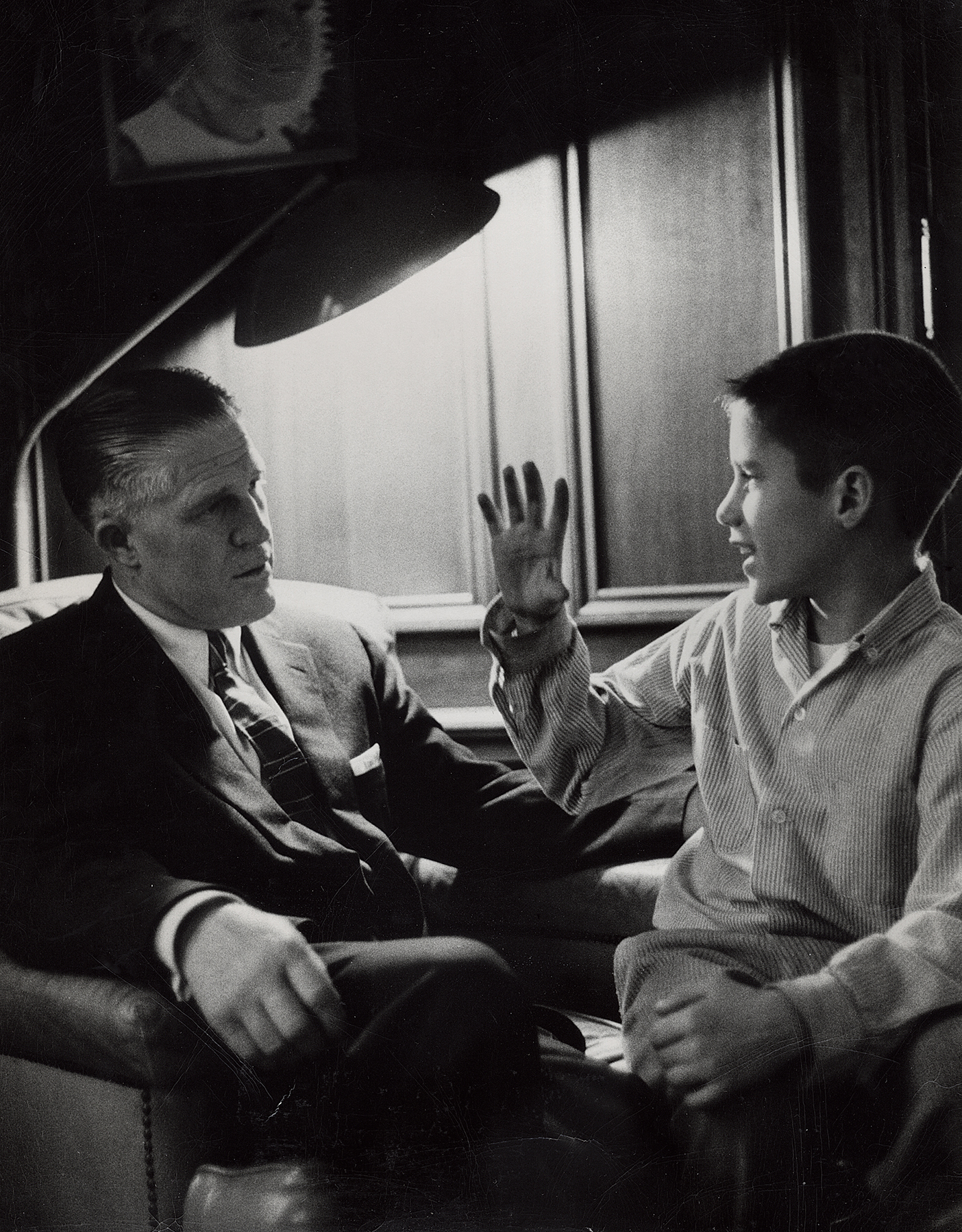 a black and white photo of Romney in a suit with a young son sitting next to him