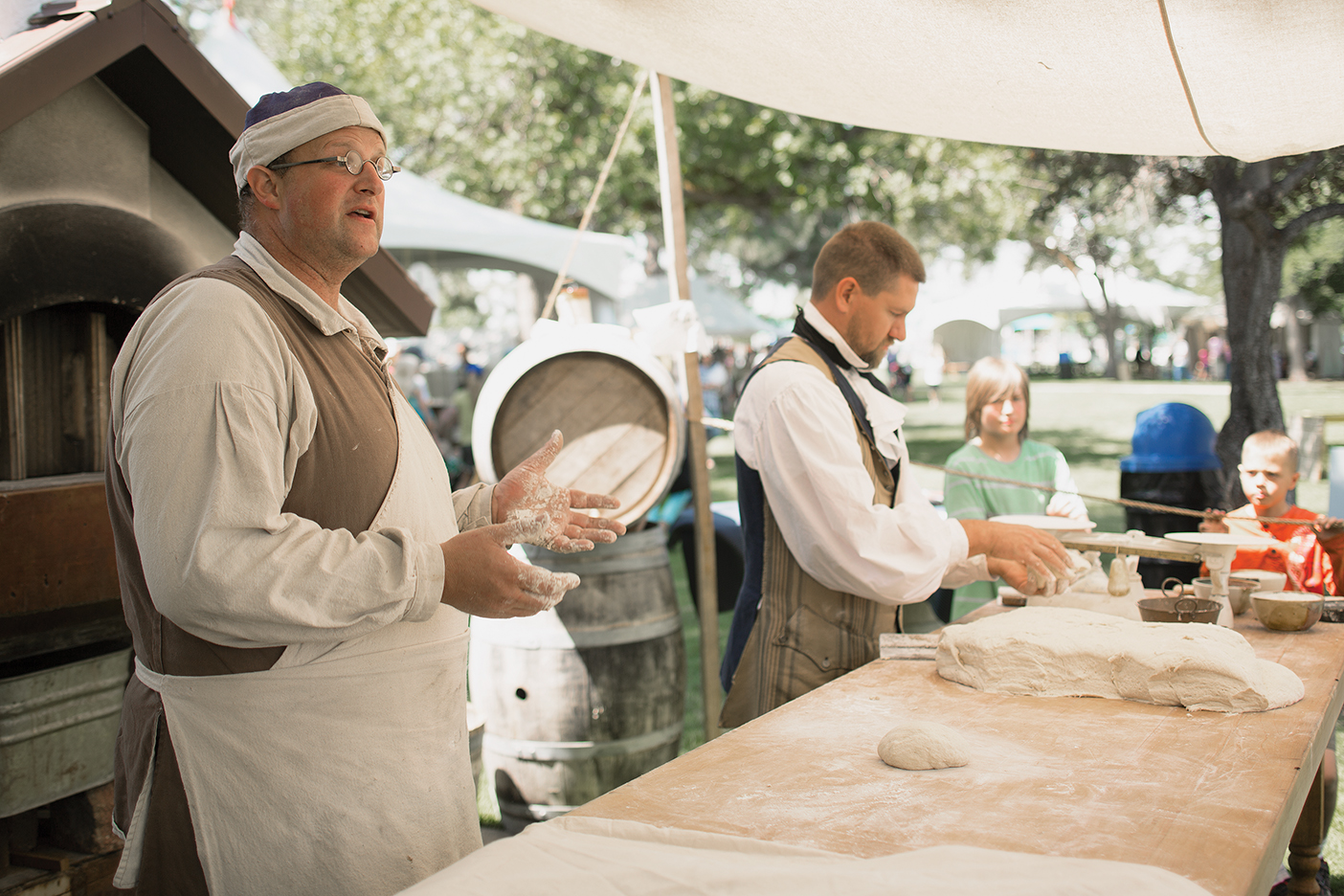 Gove Allen dressed in period costume making bread under a tent