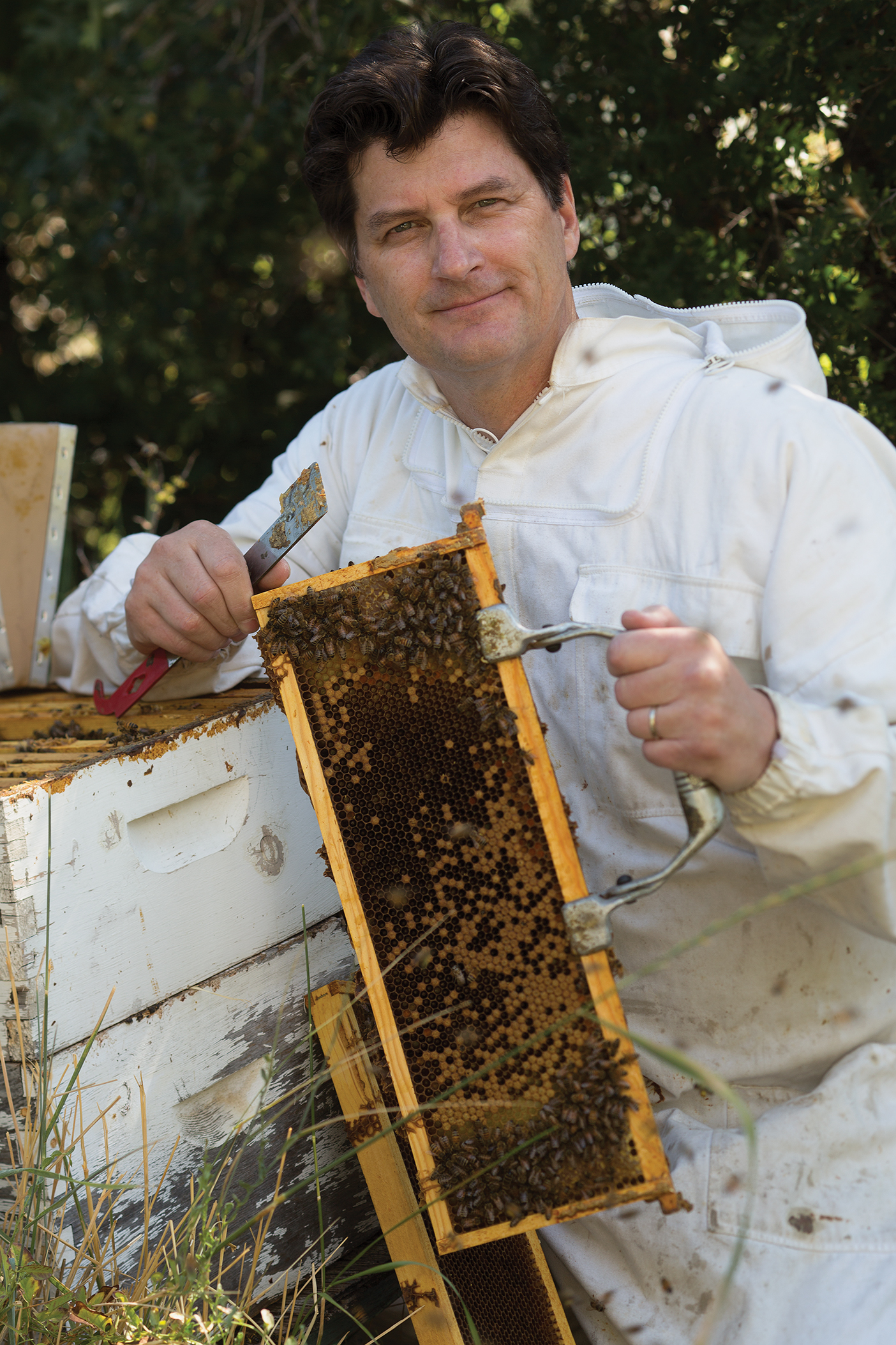 Quint Randle wearing a beekeeper outfit and holding a honeycomb tray