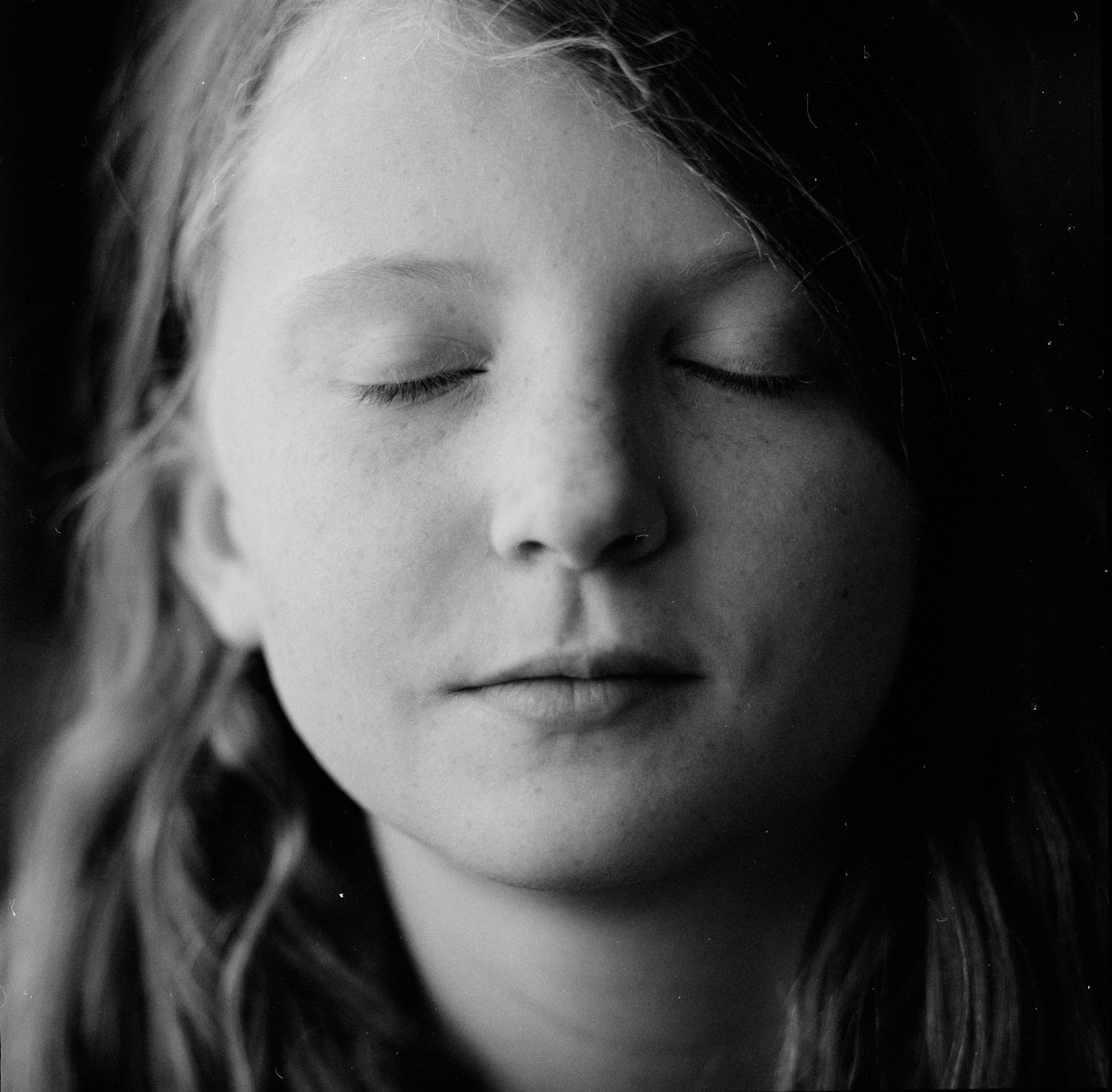 A black-and-white photo of the author's daughter, who is closing her eyes