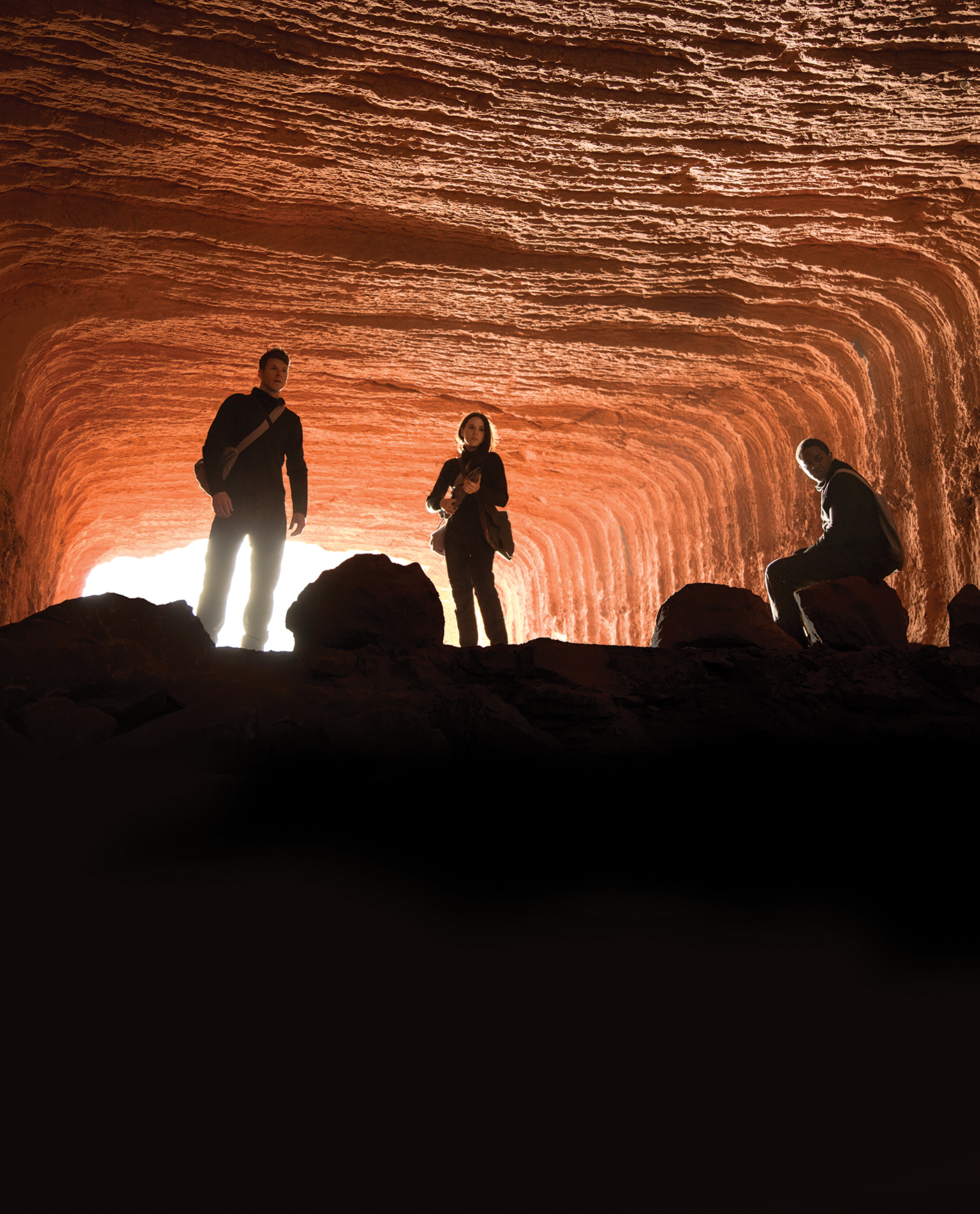 Characters from the new BYUtv show Extinct pose dramatically in a red-rock tunnel.