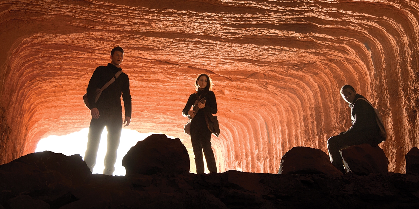 Characters from the new BYUtv show Extinct pose dramatically in a red-rock tunnel.
