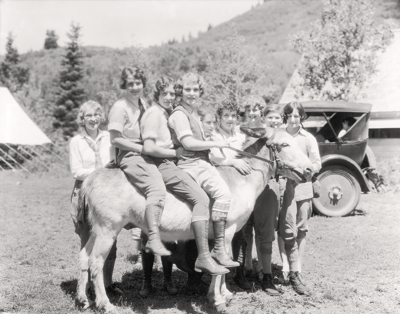 Three female students sit a top a burro at the Alpine Summer School. Photo from BYU Special Collections.