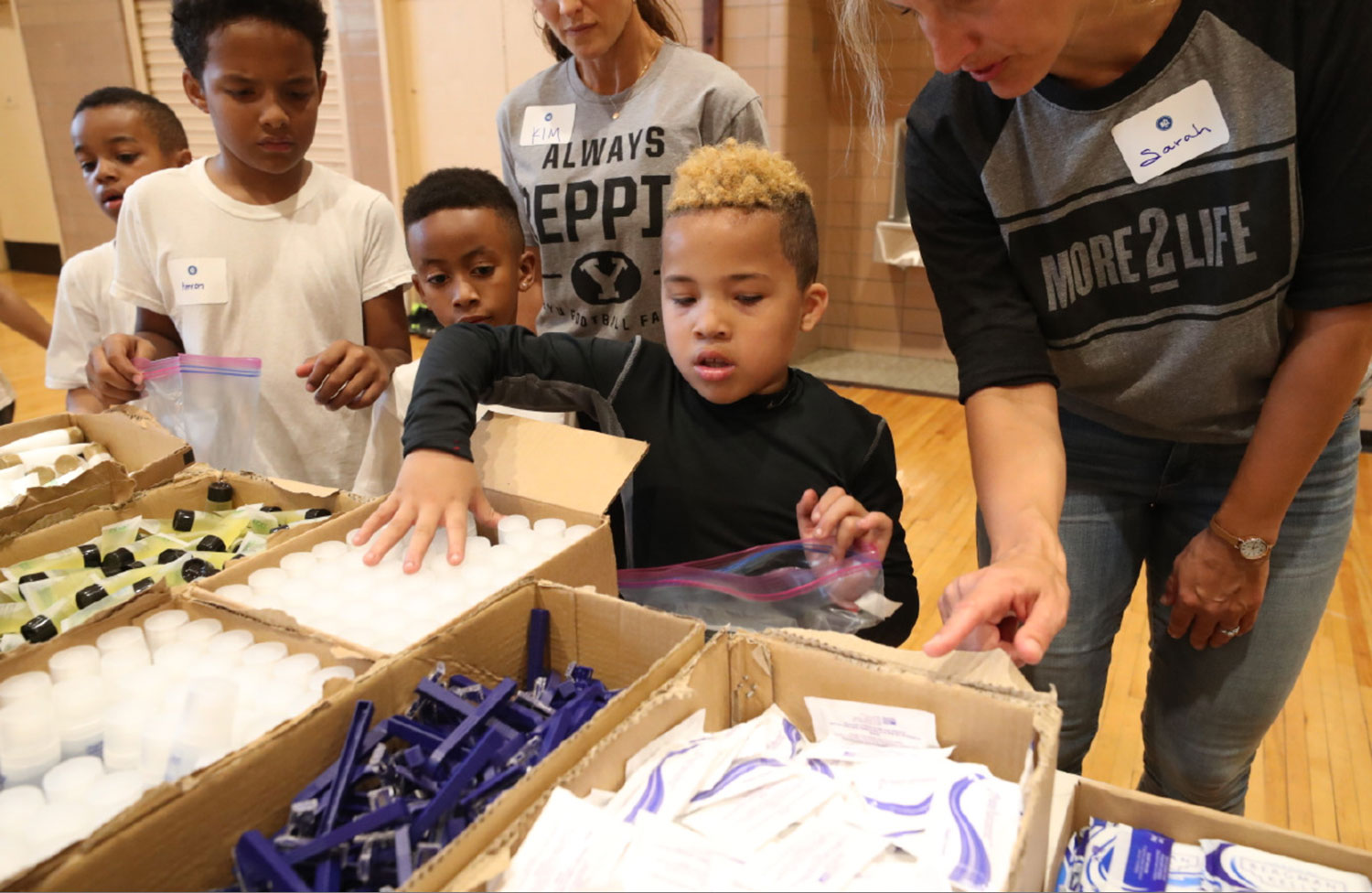 Kids line up to help build hygiene kits as part of a service project.
