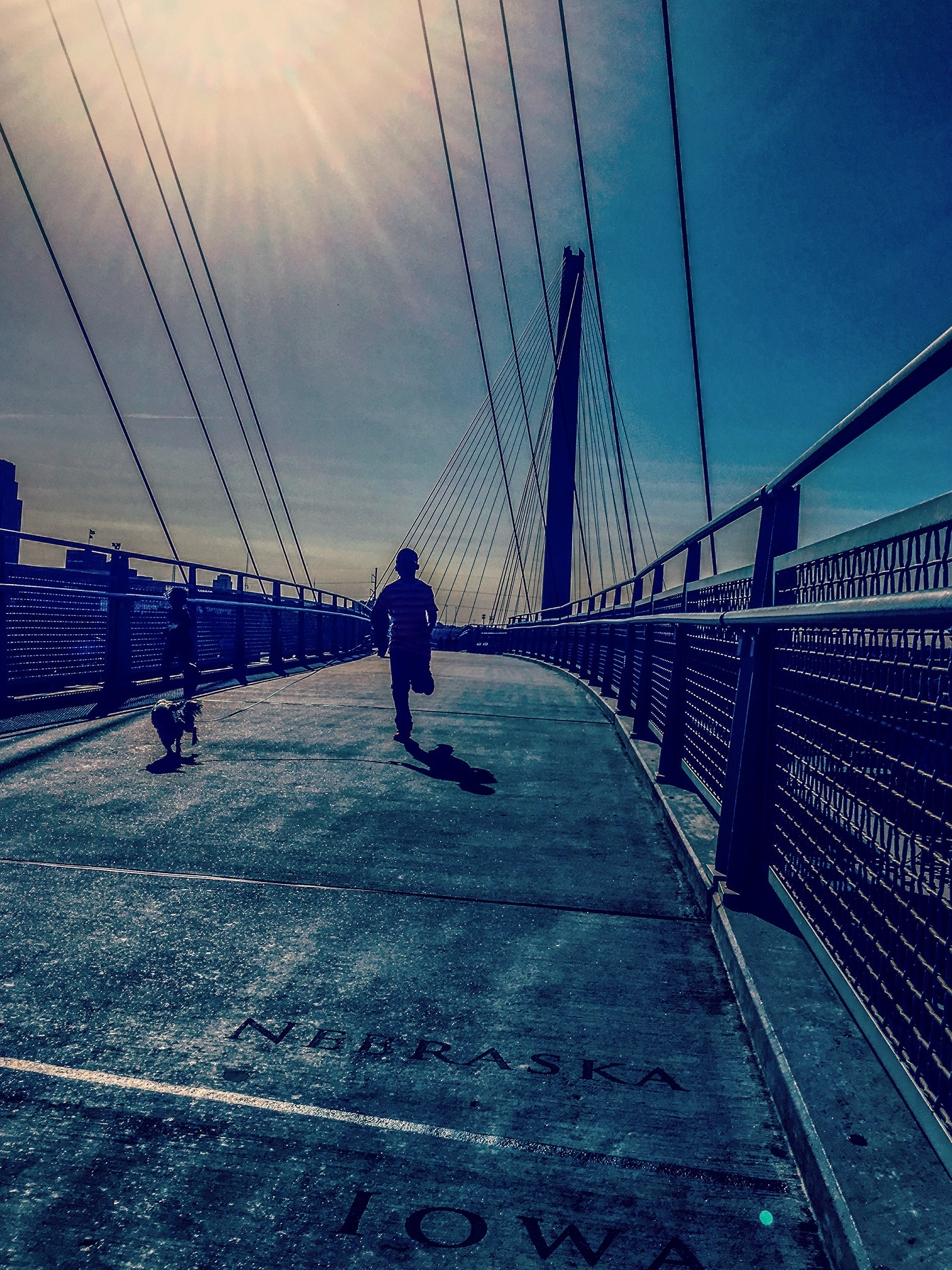 Child and dog running across the Bob Kerrey Pedestrian Bridge connecting Omaha, Nebraska, and Council Bluffs, Iowa.