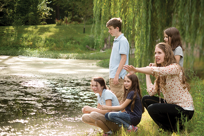 Jean Knight Pace crouches on a river bank next to her four children.