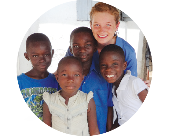 A BYU student poses for a picture with four young Ghanaian children