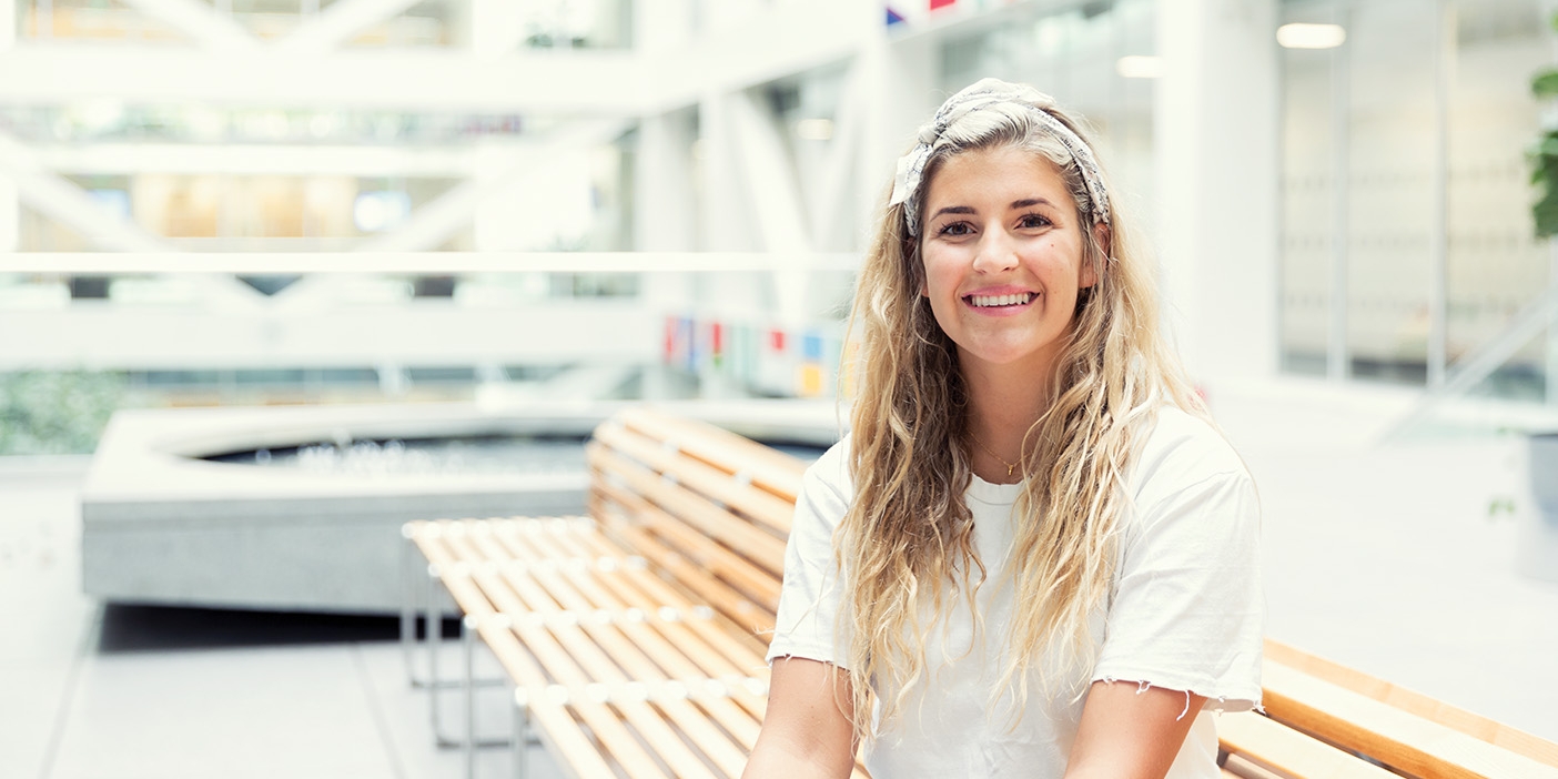 Savanna Gallacher sits on a wooden bench and smiles at the camera.