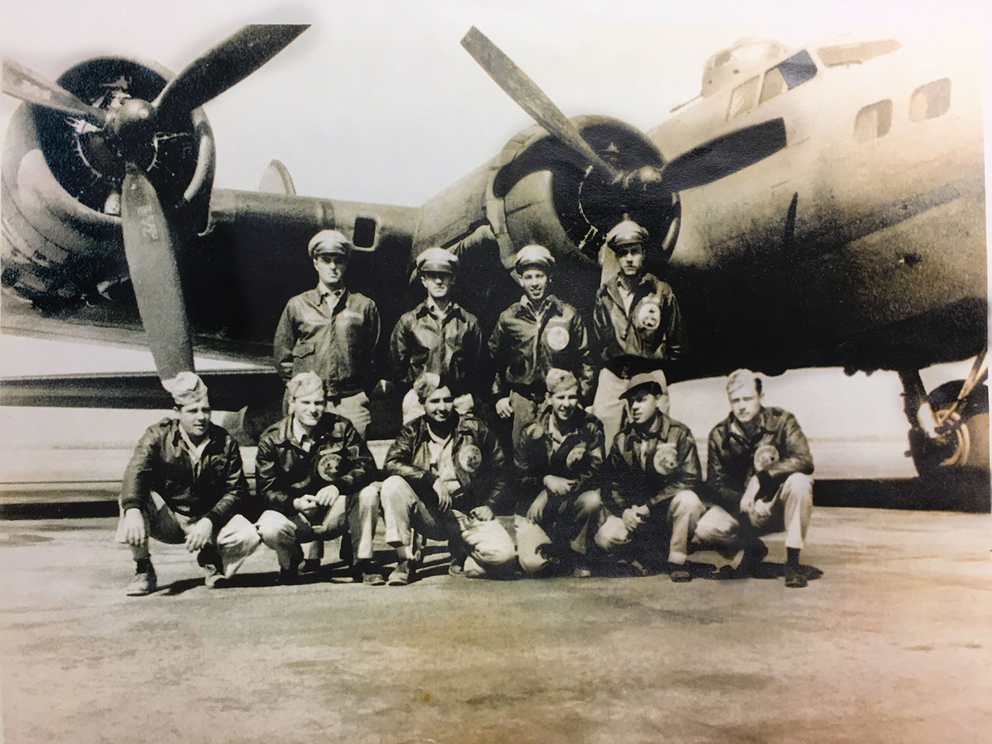 A WWII bomber crew posing in front of a B-17 bomber.