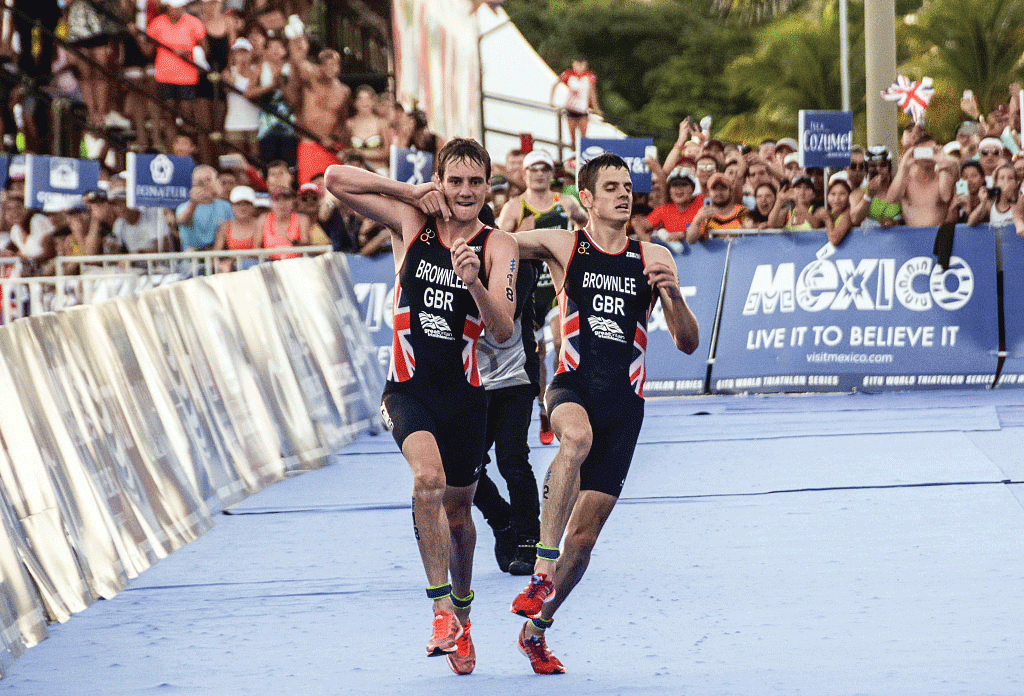 Alistair Brownlee supports his brother Jonny as they both run towards the finish line.