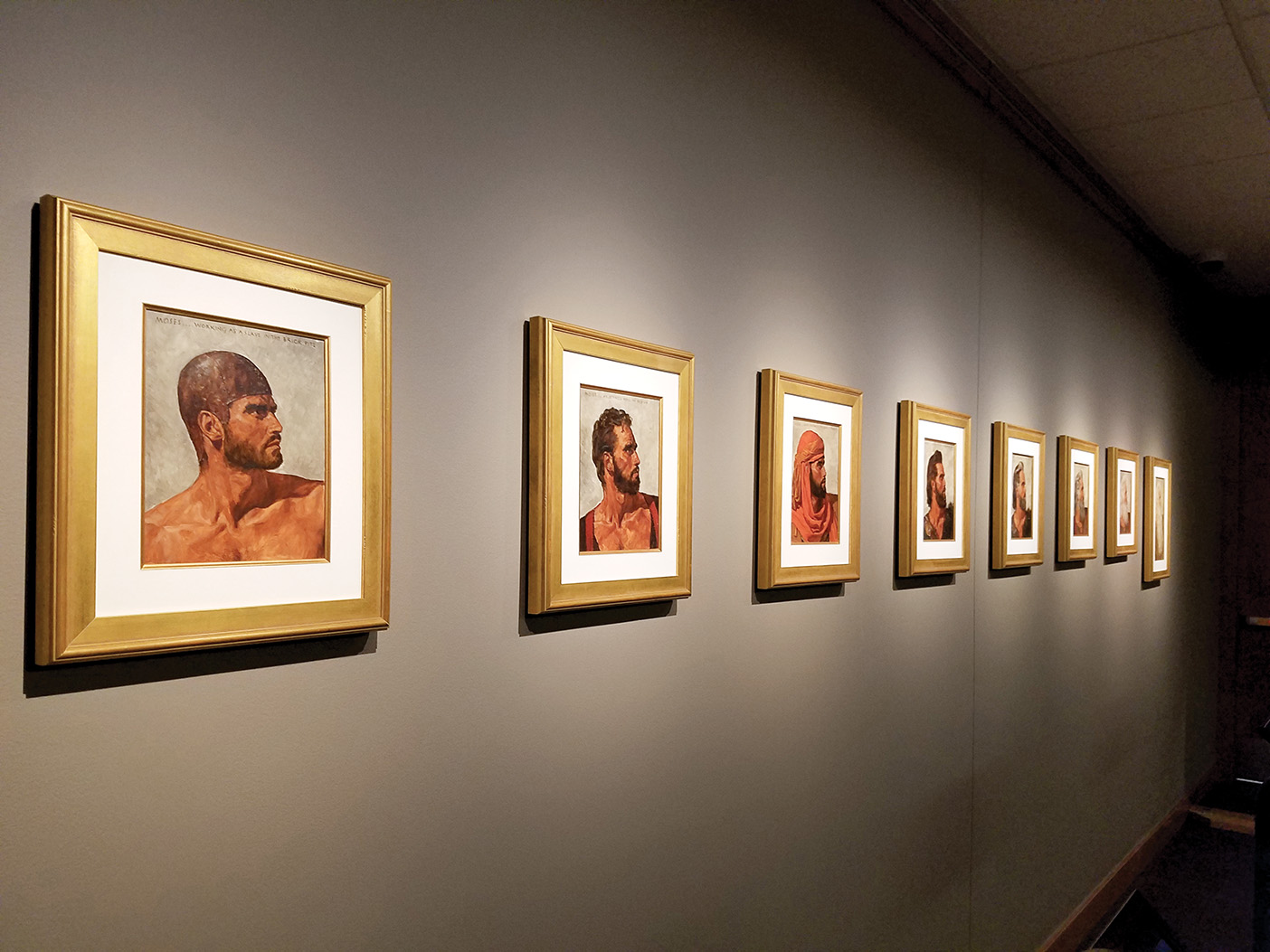 A line of portraits along the wall showing a man's head.