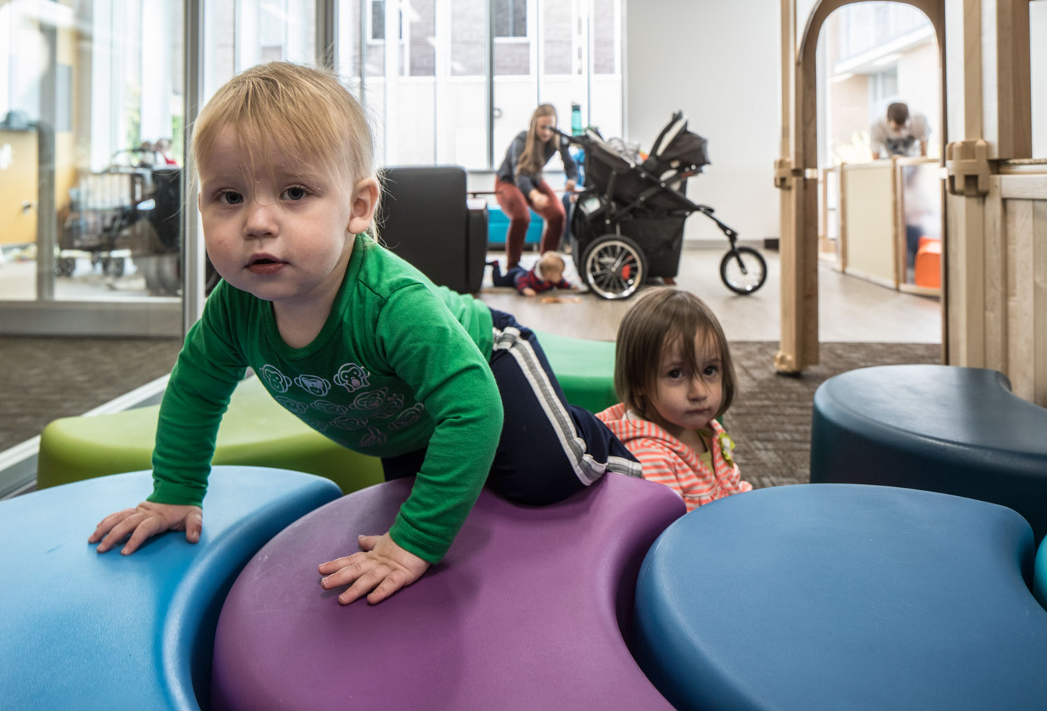 Children climb on giant, colorful, crescent-moon shaped cubes n the new family study room