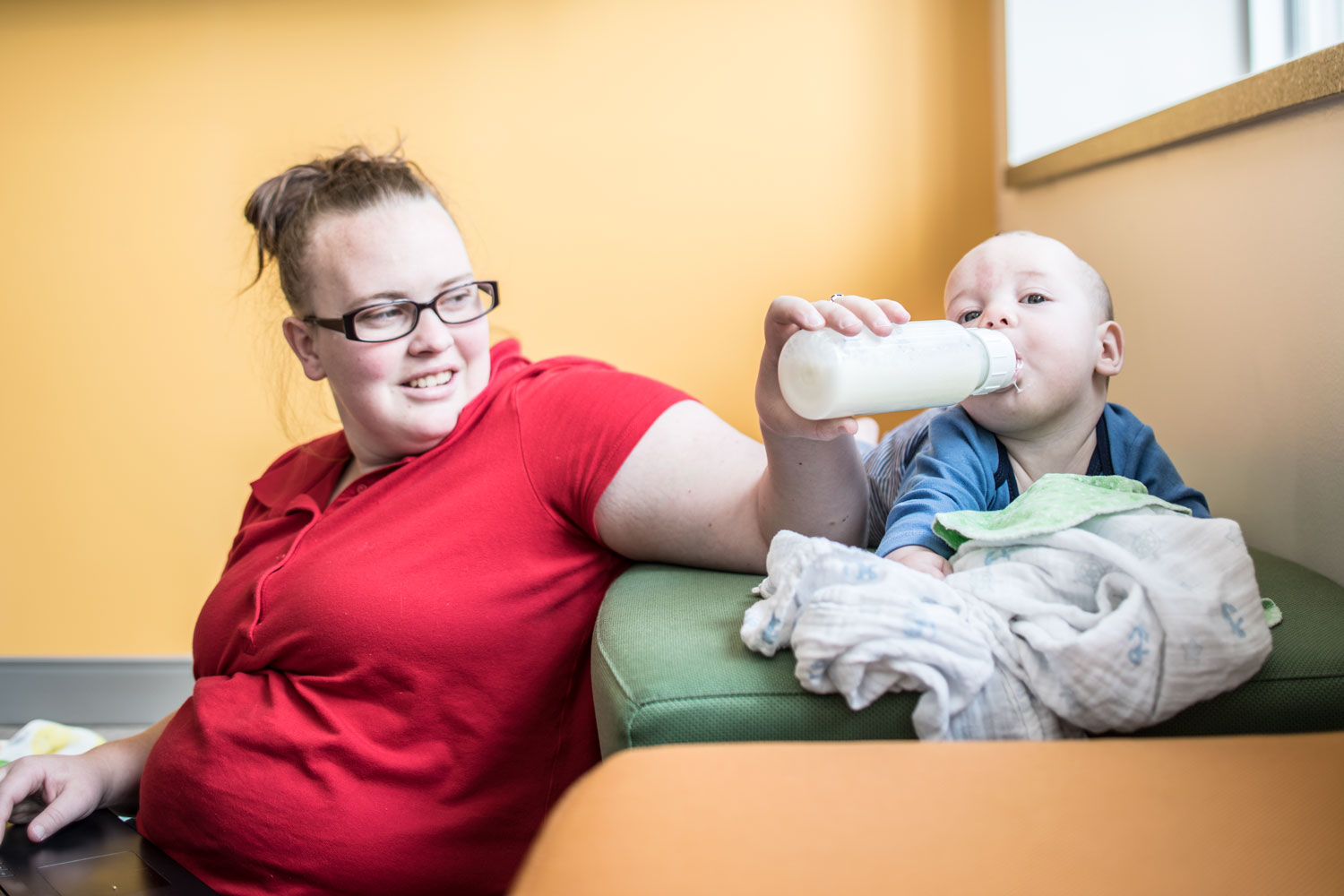 A mom feeds her son a bottle in the new family study room