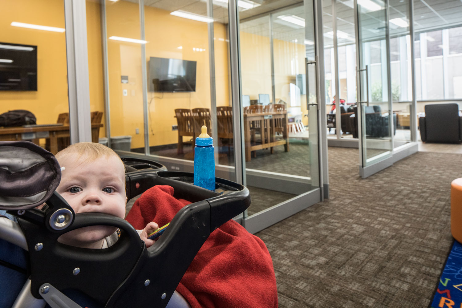 A baby teethes on the handle of its stroller n the new family study room