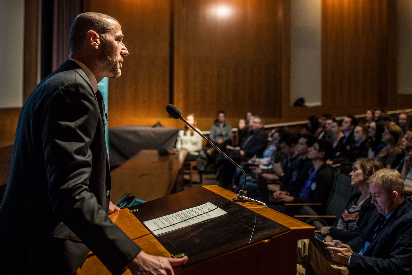 Adam Miller standing at a podium, facing a large crowd.