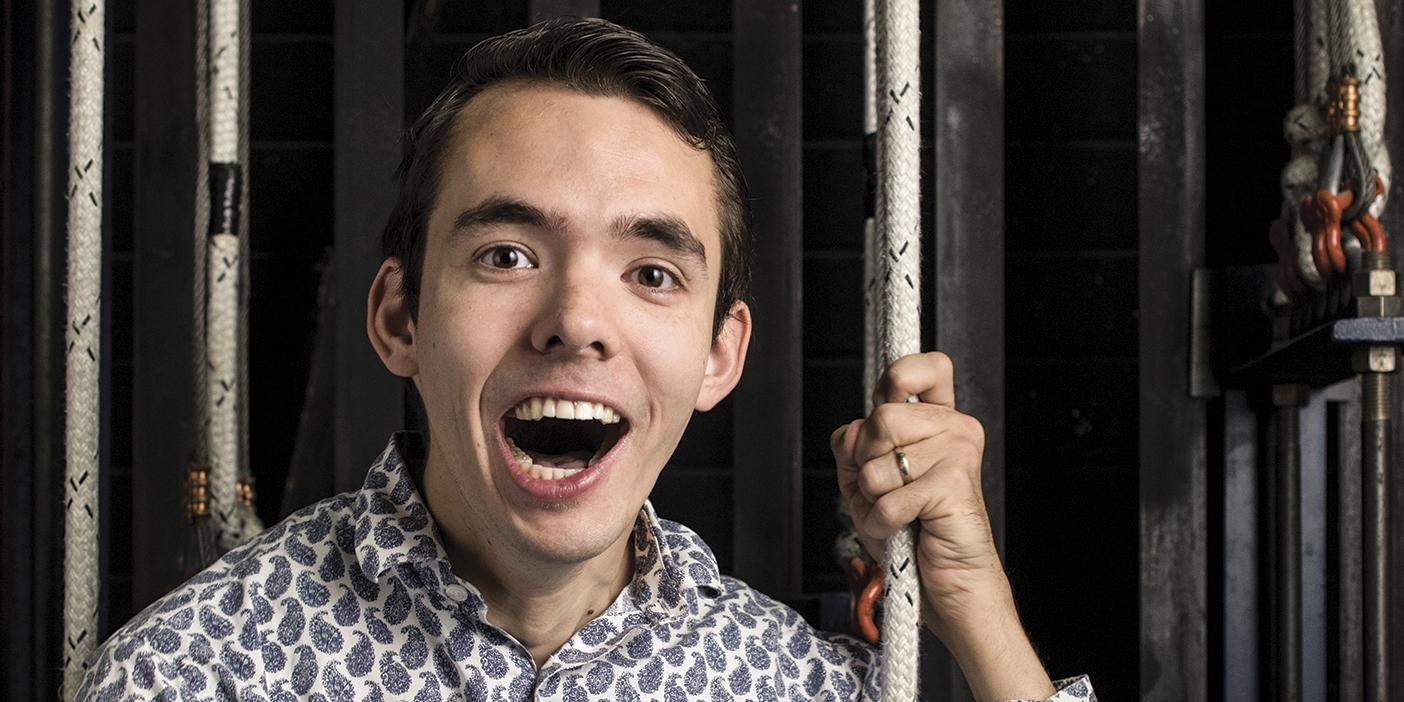 A photo of Andrew Justvig next to the ropes that pull the curtain for a BYU production.