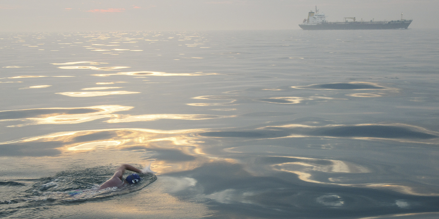 Kurt Dickson swims through the English Channel with a boat off in the distance.