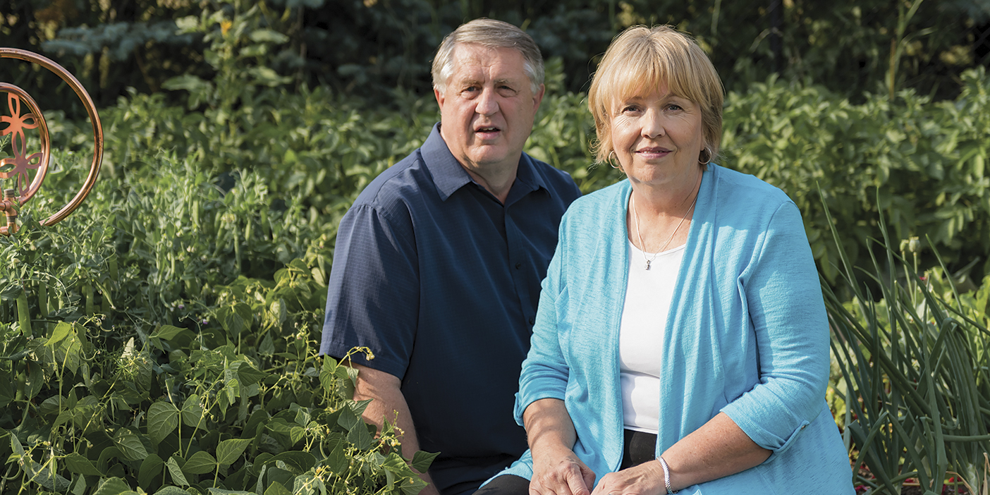 Don and Jann Smith smiling into the camera in front of greenery.