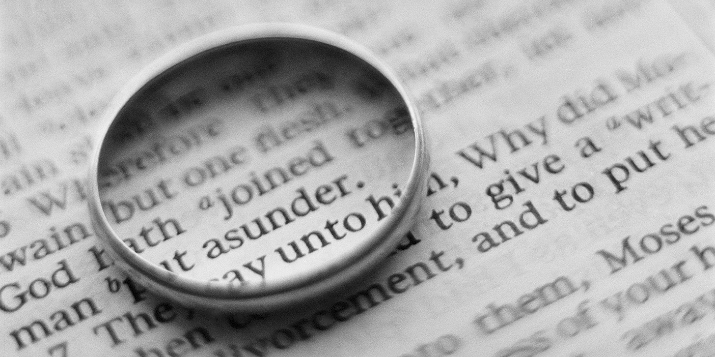 A photo of a wedding ring lying on top of a text. The ring circles the word "joined" in the text.