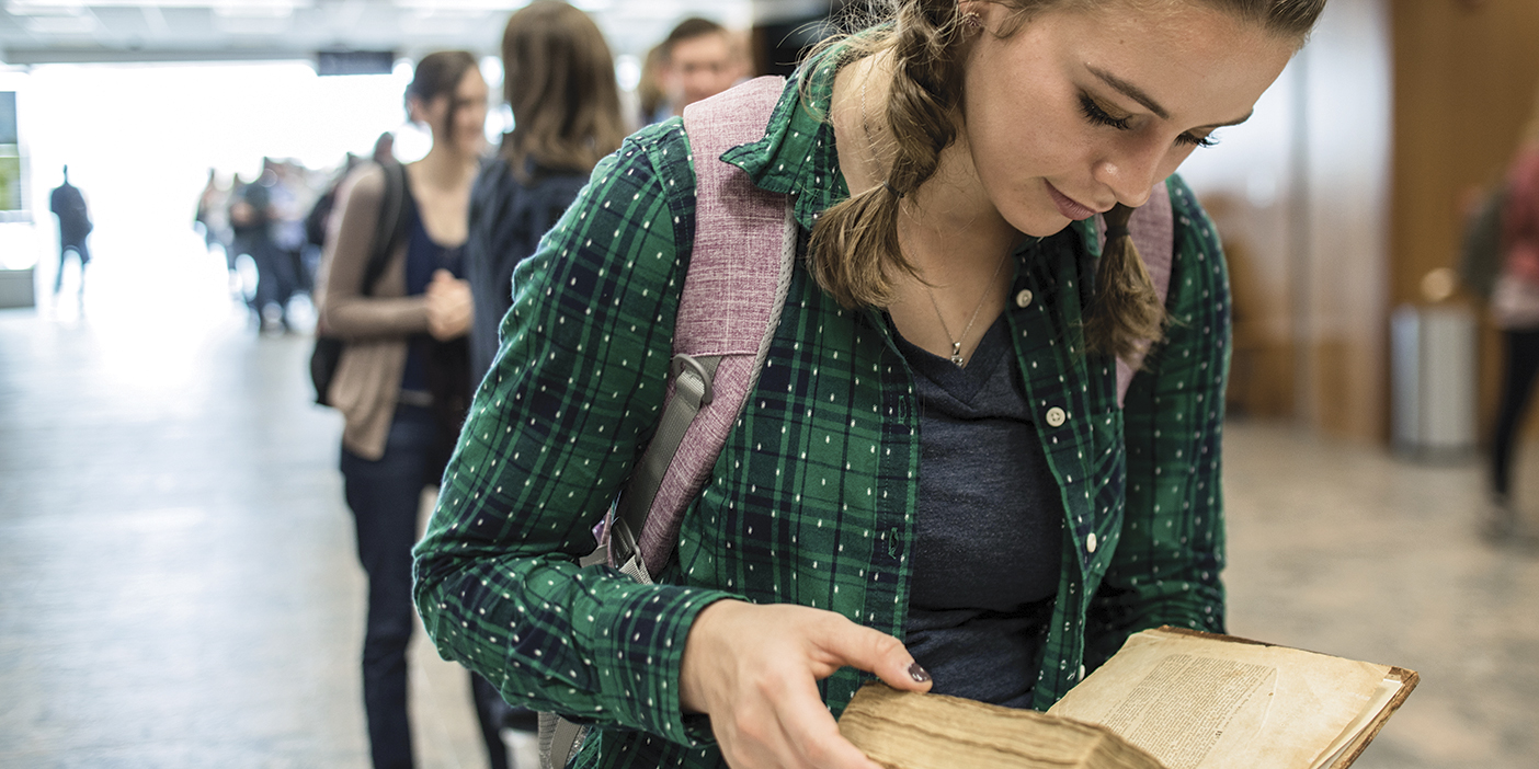 Student Rachel King holds a first-edition copy of the Book of Mormon inside the BYU library.