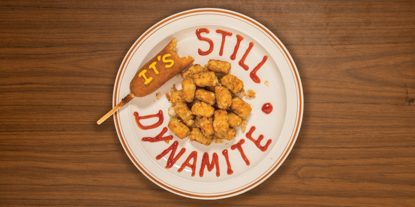 A photo of a plate of tater tots with a corndog. The title of the story is written in mustard and ketchup on the plate.