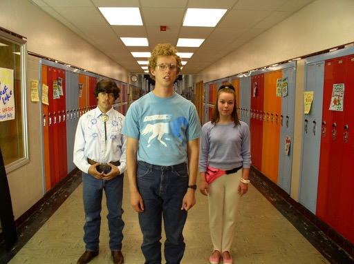 A shot of Napoleon, Pedro, and Deb, all in costume in the Preston High hallway with the multicolored lockers.