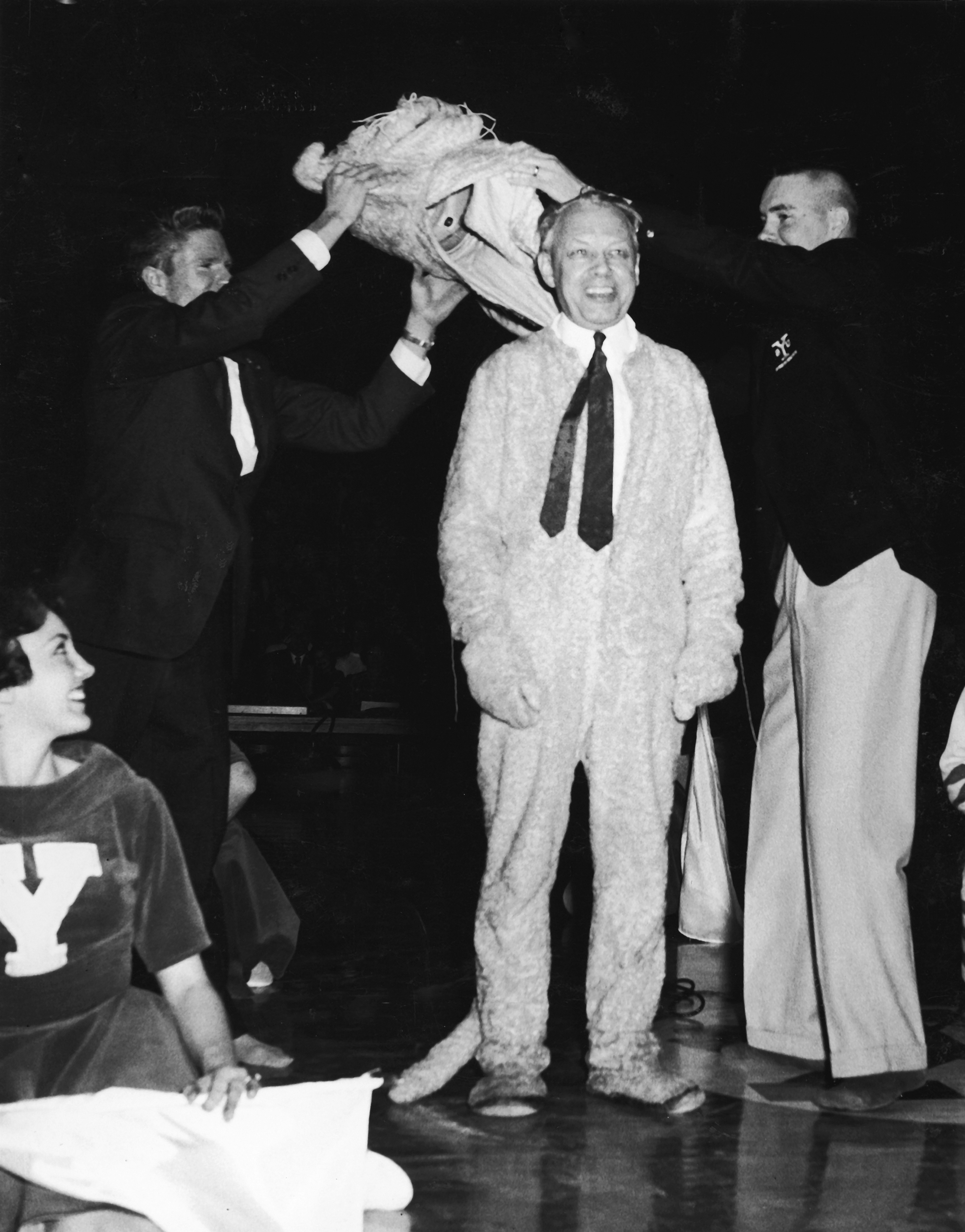 BYU president Ernest L. Wilkinson stands smiling as he is revealed as the man inside the Cosmo mascot suit.