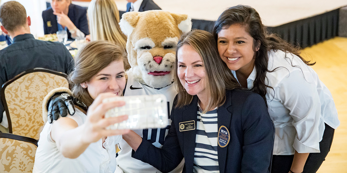 BYU Alumni president Amy Fennegan poses with students and Cosmo the cougar at an Alumni event.