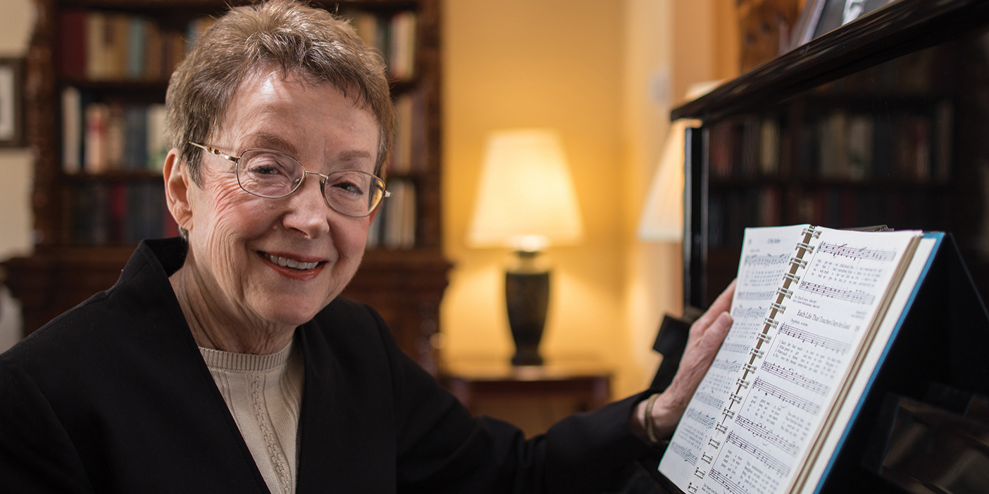 Poet and hymn writer Karen Davidson sitting at a piano.