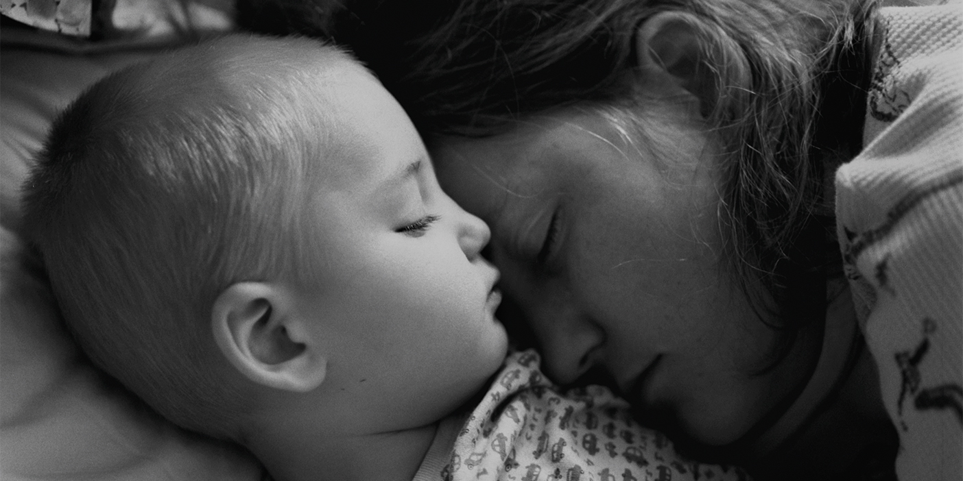 A black and white photo of a mother and child sleeping together.