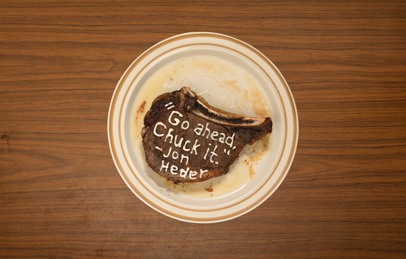 A photo of a steak on a plate. On the steak, the following quote is written in mayo: "Go ahead. Chuck it."