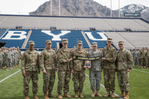 Members of BYU Army ROTC stand on the field in LaVell Edwards Stadium holding the banner for the MacArthur Award