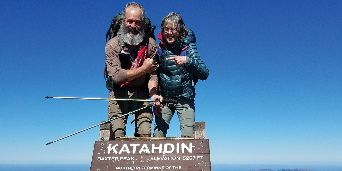 John and Shauna Dickson kiss over a trail sign on the Appalachian Trail