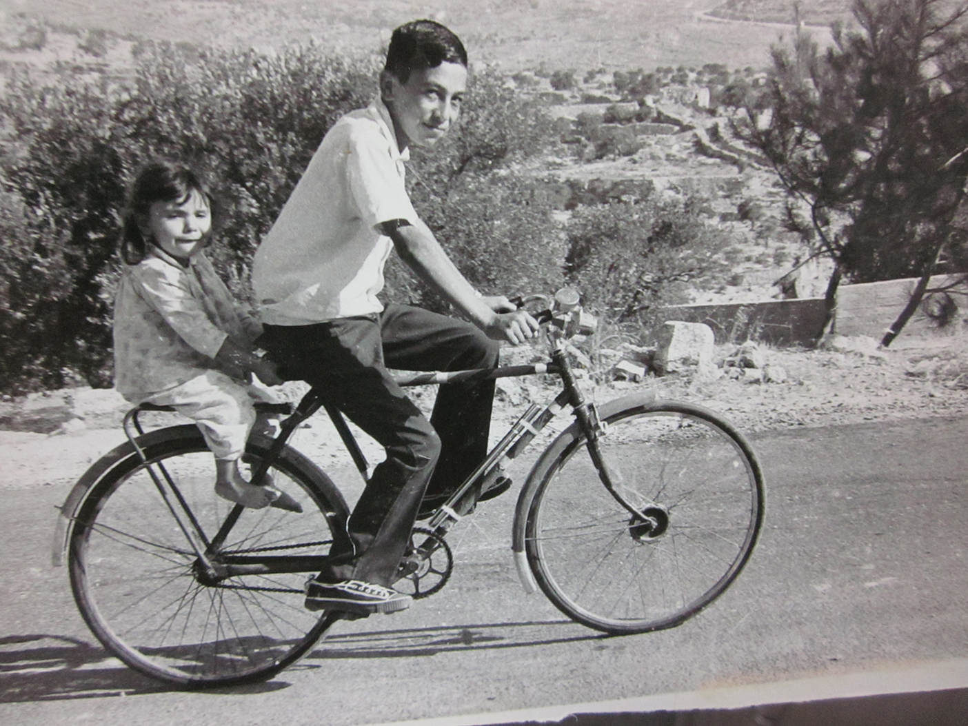 Sahar Qumsiyeh as a child riding behind her brother Walid on a bicycle.