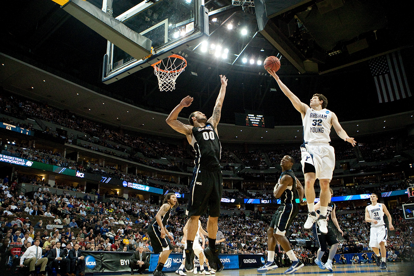 Several feet in the air, Jimmer Fredette reaches past a block from an opposing team's player to make a shot for the basket in the Marriott Center.