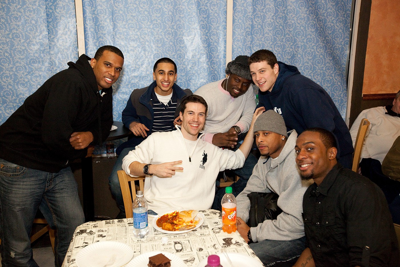 Jimmer Fredette with his older brother, TJ, and five other friends around a table in a home.