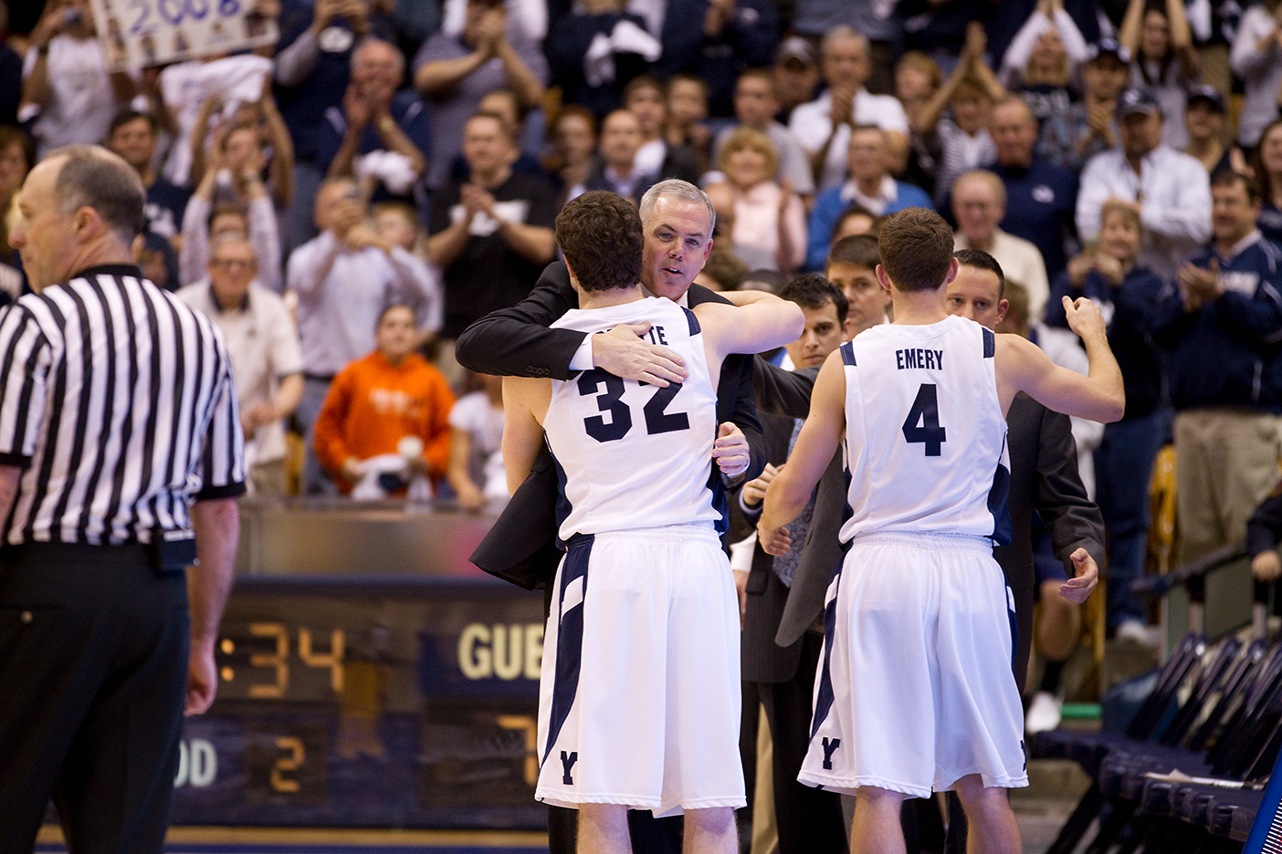 Coach Dave Rose and Jimmer Fredette hug at a BYU game as fans watch from the stands.