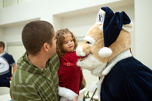 Cosmo, dressed in a blue Santa suit, meets a little girl and her father.