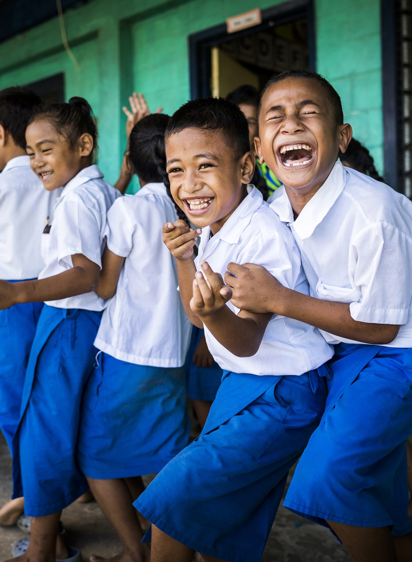 Three young Samoan students laugh together.
