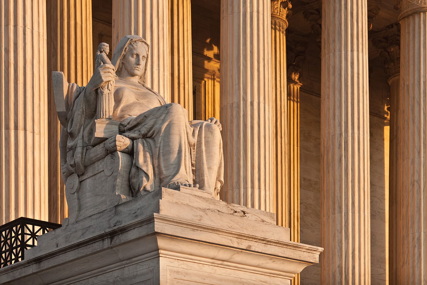 A marble statue outside the U.S. Supreme Court of a woman sitting in a chair acting as a judge.
