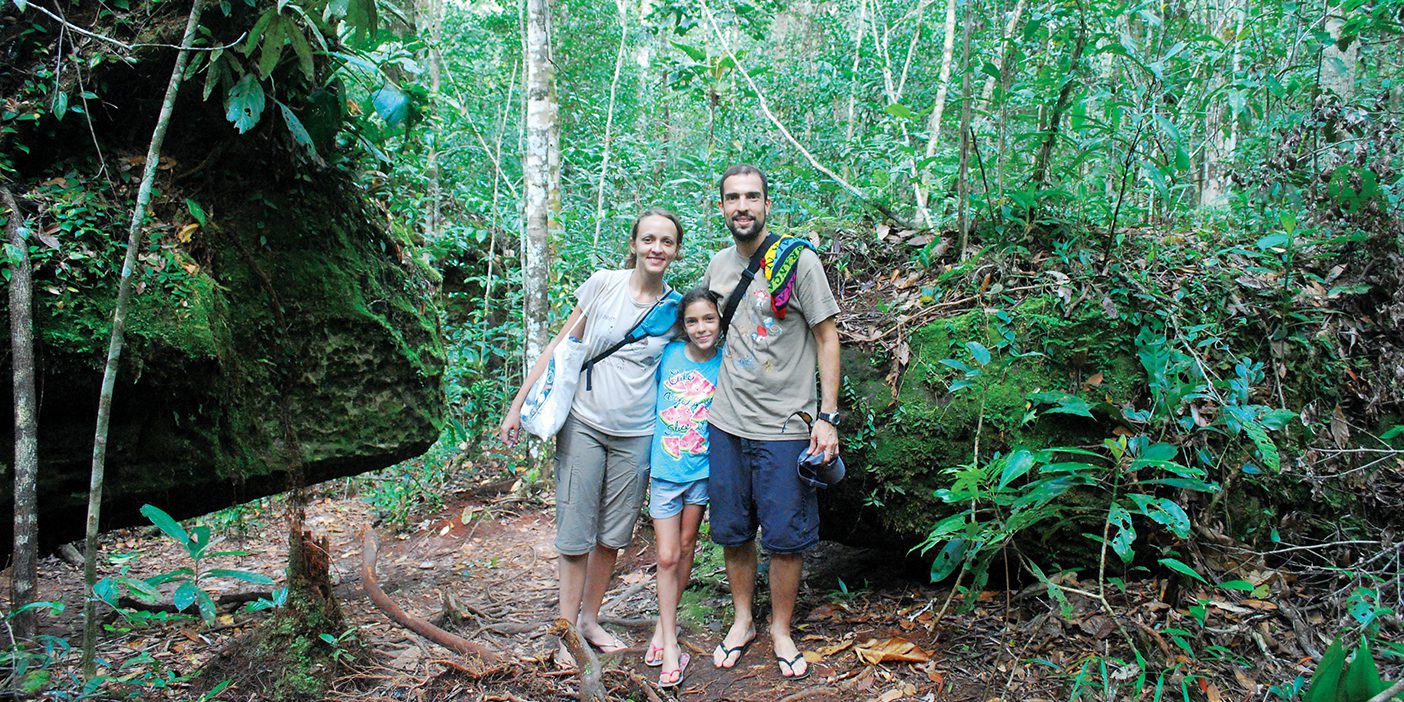 Fernanda Werneck and Rafael Leite, scientists at the National Institute for Amazon Research in Manaus, Brazil, stand in a patch of Amazon forest with their daughter, Iara.
