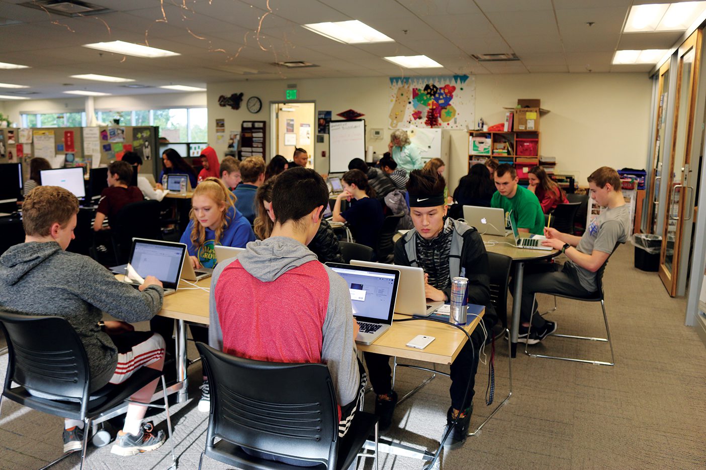 High school students work on college prep coursework on laptops in a classroom.