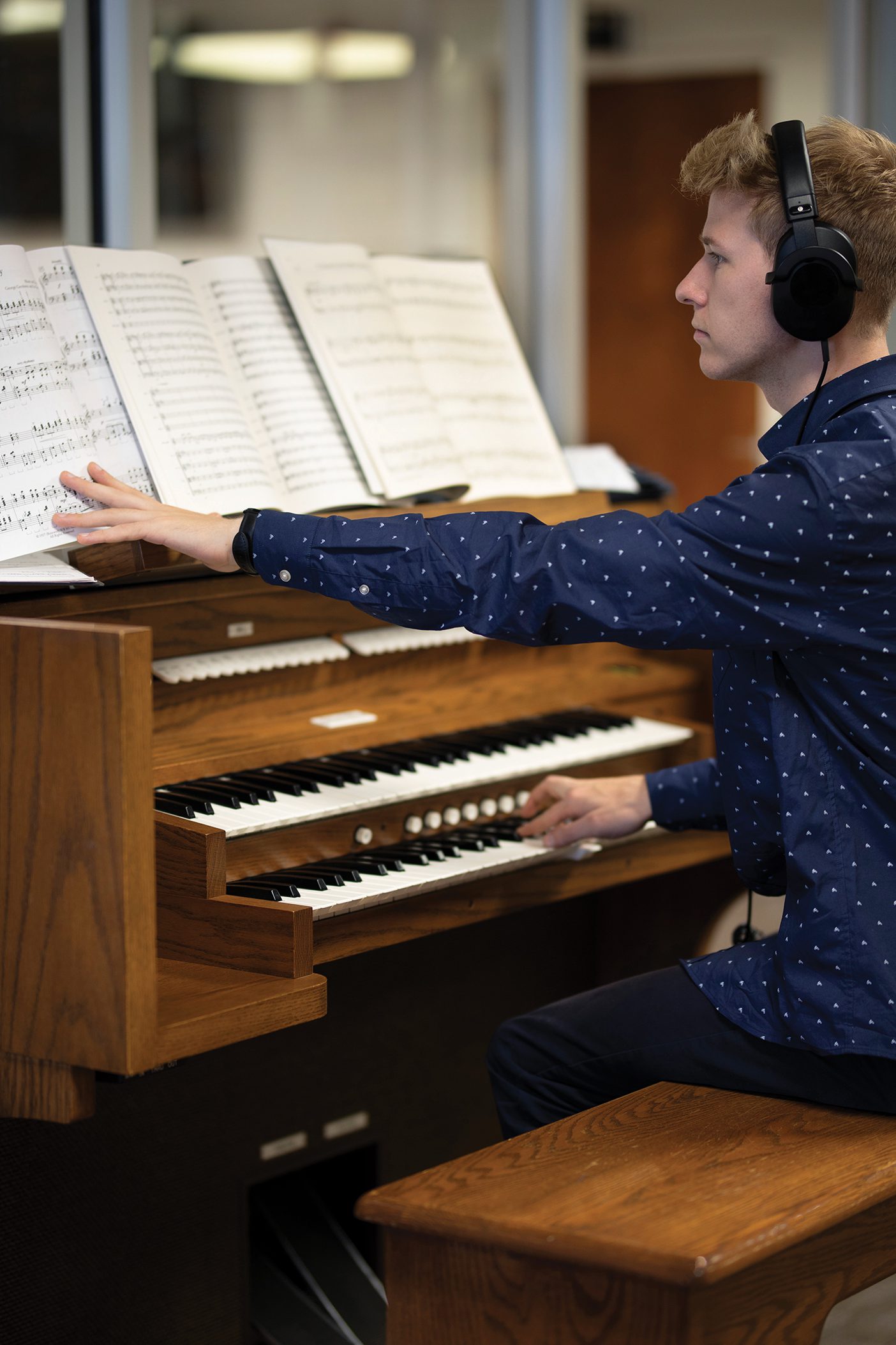 While wearing headphones, a student practices on an electric organ.