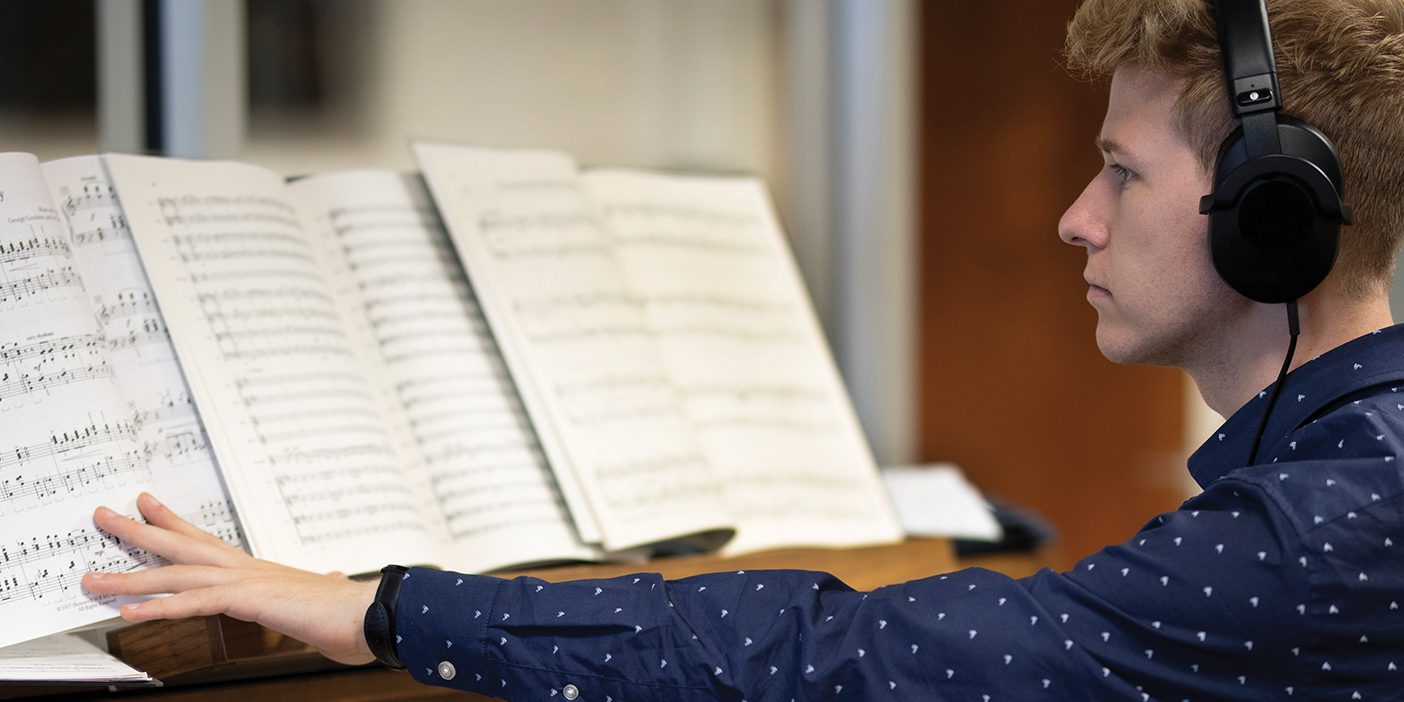 While wearing headphones, a student practices on an electric organ.