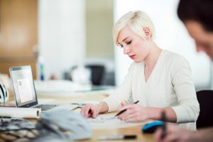 A young woman concentrating on studying at a table in a bright room
