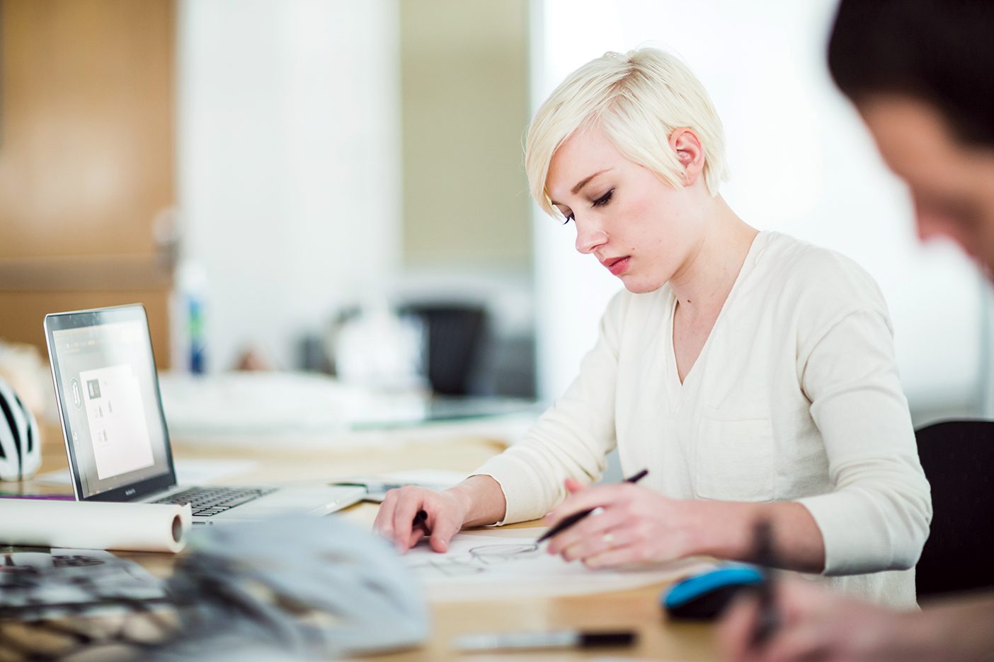 A young woman concentrating on studying at a table in a bright room