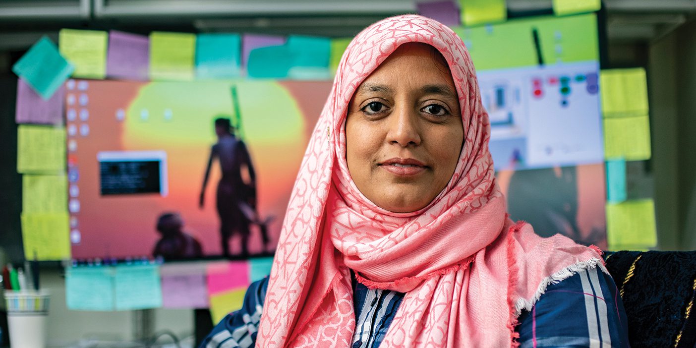 PhD student Meher Shaikh sits in front of her computer, which is ringed with colorful sticky notes.