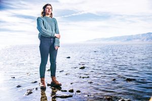 Looking off into the distance, a woman stands in a body of water.